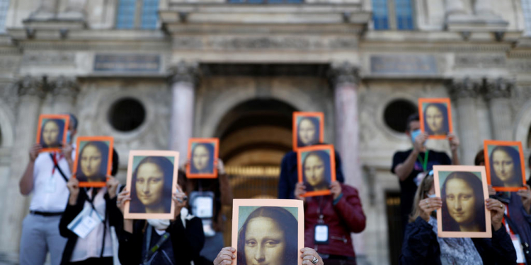 Paris tour guides hold posters depicting Mona Lisa painting by artist Leonardo da Vinci during an action at Le Louvre museum courtyard to warn on their working conditions in Paris as the museum reopens its doors to the public after almost 4-month closure due to the coronavirus disease (COVID-19) outbreak in France, July 6, 2020. REUTERS/Christian Hartmann