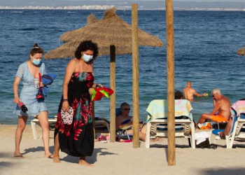 Tourists walk at Palmanova Beach on the Island of Mallorca on July 27, 2020. - Tour operator TUI has cancelled all British holidays to mainland Spain from today until August 9, after the UK government's decision to require travellers returning from the country to quarantine. (Photo by JAIME REINA / AFP)