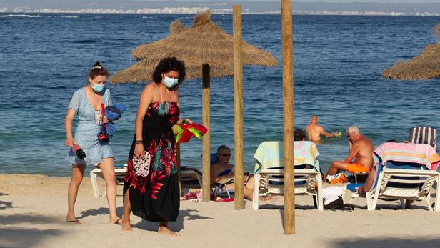 Tourists walk at Palmanova Beach on the Island of Mallorca on July 27, 2020. - Tour operator TUI has cancelled all British holidays to mainland Spain from today until August 9, after the UK government's decision to require travellers returning from the country to quarantine. (Photo by JAIME REINA / AFP)