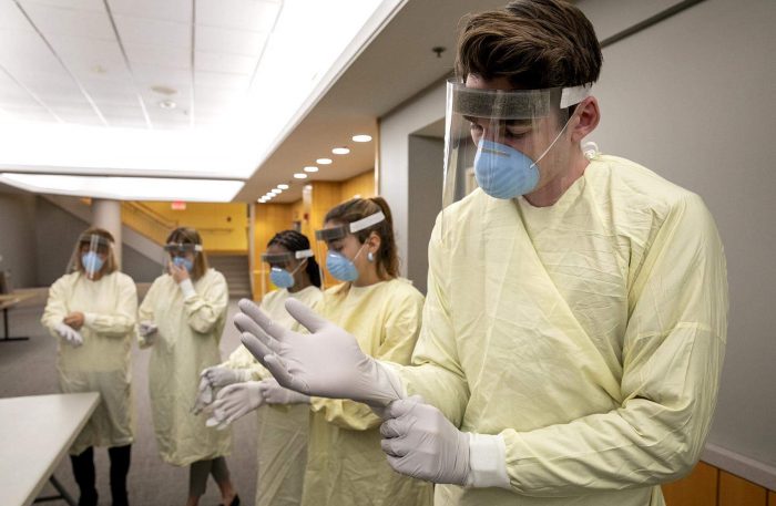 Clinical Care Technician John Martin pulls on gloves at protective equipment training session at Tufts Medical Center. (Robin Lubbock/WBUR)