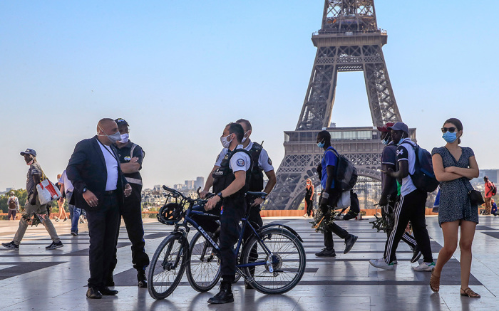 Police officers talk to a man while wearing protective face masks as precaution against the conoravirus at Tocadero plaza near Eiffel Tower in Paris, Monday, Sept. 14, 2020. France sees a substantial increase of Covid-19 cases. (AP Photo/Michel Euler)
