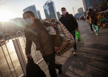 People wear face masks as they walk outside a bus terminal following an outbreak of the coronavirus disease (COVID-19) in Beijing, China, December 10, 2020.   REUTERS/Thomas Peter