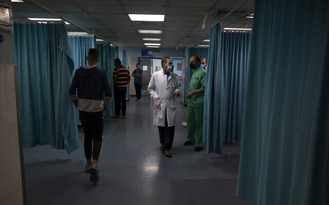 Palestinian doctors and medics walk inside the emergency room of the Shifa hospital in Gaza City, Thursday, May 13, 2021. Just weeks ago, the Gaza Strip’s feeble health care system was struggling with a runaway surge of coronavirus cases. Now doctors across the crowded coastal enclave are trying to keep up with a very different crisis: blast and shrapnel wounds, cuts and amputations. (AP Photo/Khalil Hamra)