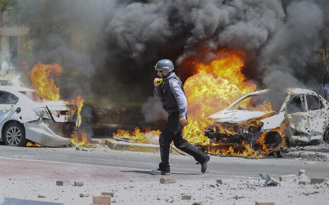 An Israeli firefighter walks next to cars hit by a missile fired from Gaza Strip, in the southern Israeli town of Ashkelon, Tuesday, May 11, 2021. (AP Photo/Ariel Schalit)