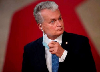 Lithuania's President Gitanas Nauseda takes off his protective face mask as he prepares to make a statement on arrival for an EU summit at the European Council building in Brussels, Friday, July 17, 2020. Leaders from 27 European Union nations meet face-to-face on Friday for the first time since February, despite the dangers of the coronavirus pandemic, to assess an overall budget and recovery package spread over seven years estimated at some 1.75 trillion to 1.85 trillion euros. (AP Photo/Francisco Seco, Pool)