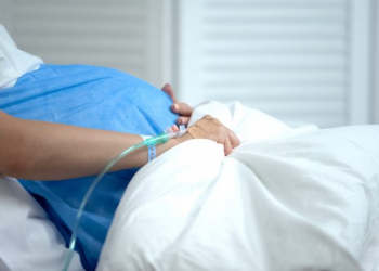 Pregnant woman holding blanket, feeling abdominal pain, risk of miscarriage