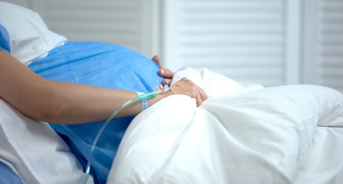 Pregnant woman holding blanket, feeling abdominal pain, risk of miscarriage