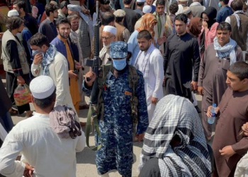 A member of Taliban security forces stands guard among crowds of people walking past in a street in Kabul, Afghanistan September 4, 2021. REUTERS/Stringer - RC2YIP9MNRZG