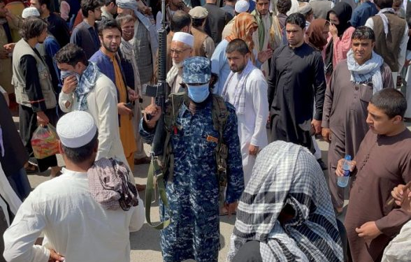 A member of Taliban security forces stands guard among crowds of people walking past in a street in Kabul, Afghanistan September 4, 2021. REUTERS/Stringer - RC2YIP9MNRZG